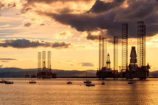 Scotland, Cromarty Firth, Oil platforms in sea at sunset
