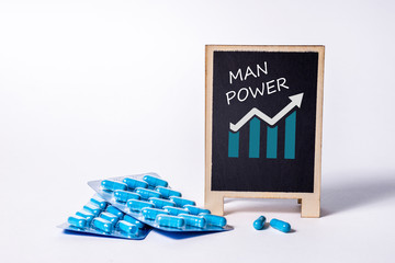 Two packs of blue capsules and the word man power on a chalkboard. Pills for men's health and...
