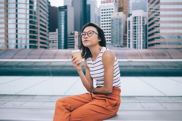 Pensive relaxed woman with coffee on bench