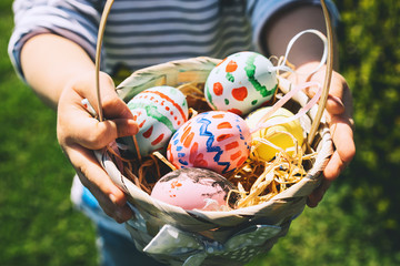 Colorful Easter eggs in basket. Kids hunt for eggs outdoors. - 324320258