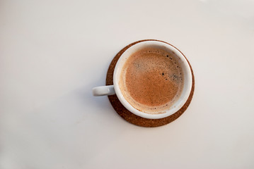 A cup of espresso coffee, a white cup on a cork stand.