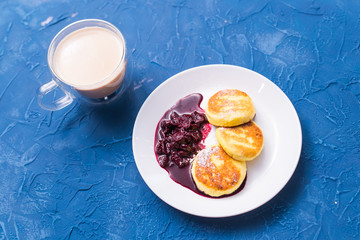 Cottage cheese pancakes with cherry jam, close up, top view.