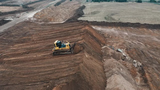 Bulldozer digging sand sandy quarry on construction apartment buildings city sleeping area view from top drone on crawler excavator controlled operator preparation of site for apartment high building.