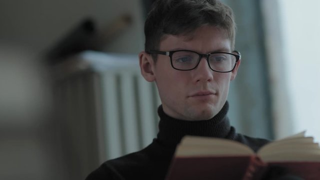 Reading a book in daylight room: man carefully in classical literature