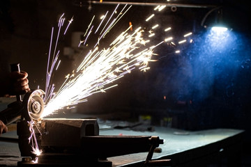 An angle grinder polishes the metal and sparks fly out of the abrasive wheel.