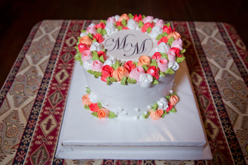 Above the MM inscription. On the background of the carpet . Cake with white, colorful round top.