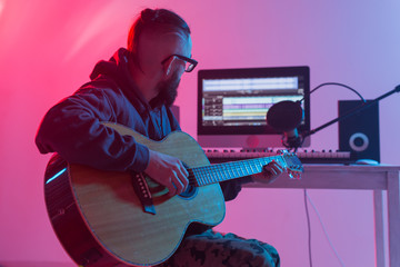 Create music and a recording studio concept - Bearded man guitarist recording electric guitar track...