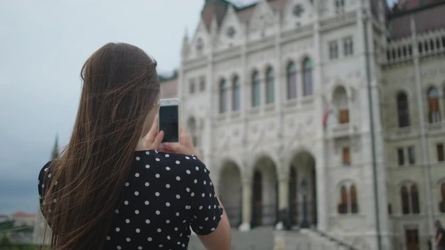 Girl taking mobile photos of Parliament Building in Budapest, Hungary