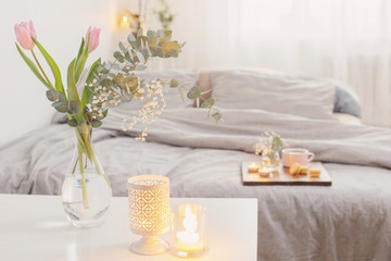 interior of bedroom with flowers, candles and cup of tea
