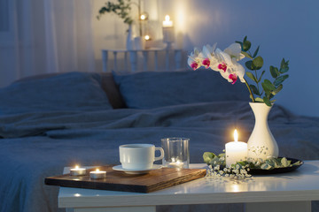 night interior of bedroom with flowers and burning candles