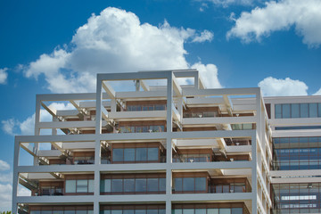 A white office tower with balconies and terraces under a bright sunny sky