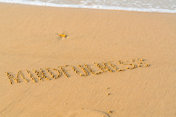 foamy sea water and Inscription mindfulness on the sandy beach