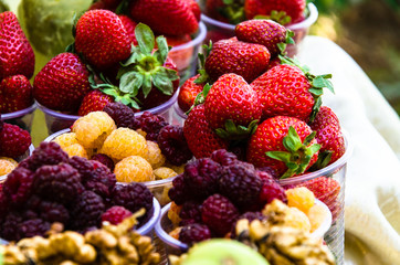 Ripe fruits in glasses for street sale. Red and white raspberries, strawberries figs, nuts. Travel and adventure.