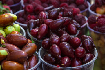 Ripe fruits in glasses for street sale. Jujube, Red and white raspberries, figs, nuts. Travel and adventure.