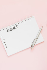 Top view of a flat lay of  desktop and notepads for writing down goals and plans. 2020 New Year's goal, plan, action text on  notepad with office accessories. Business motivation, inspiration concept.