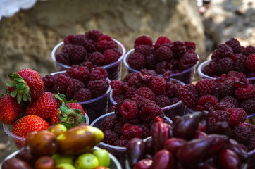 Ripe fruits in glasses for street sale. Red and white raspberries, strawberries figs, nuts. Travel and adventure.