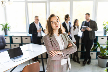 Female Business leader standing in front of her team in office