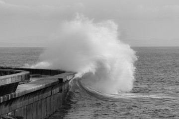 Fototapeta na wymiar Big ocean wave hitting pier. Storm waves