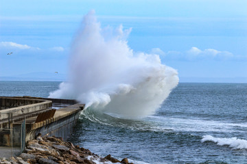 Big ocean wave hitting pier. Storm waves