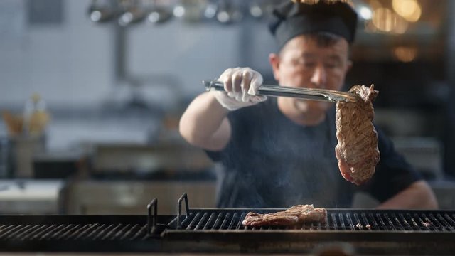Korean kitchener turning roasted meat fillet on grilled. Medium close up shot on 4k RED camera