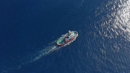 Naklejka premium Aerial drone photo of tug assisting boat cruising near commercial container area of Perama, Attica, Greece