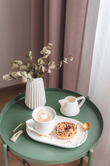 Breakfast in bed, cup with cappuccino, doughnuts, flowers white tulips, morning concept, linen bed sheets, woman's day