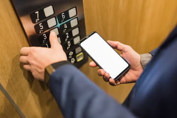 Man hands holding blank screen mobile phone while using elevator control panel. © zphoto83