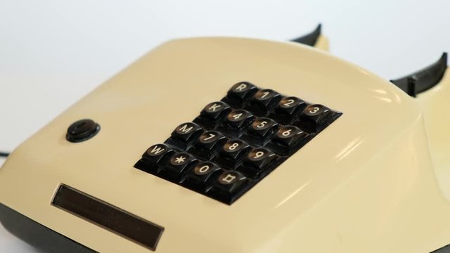Hand picks up the phone dials the number , old push-button office phone on white background. Close up.