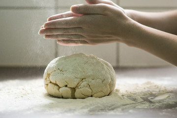 woman makes some fresh handmade  sweet pastry on the kitchen table covered with flour. DIY cake pastry baking, spreading flour with hands