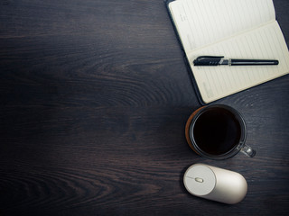 Workplace with notebook, pen and glass coffee mug on wooden background