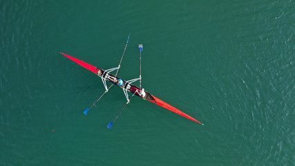 Aerial drone photo of athlete competing in canoe race in tropical lake with emerald waters