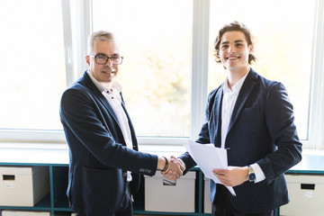 Two colleagues handshaking after meeting in office room
