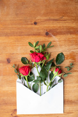 Beautiful flowers on a wooden table with an envelope. The work of the florist. Flower delivery
