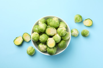 Bowl with brussels sprout on blue background, top view