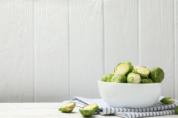 Bowl with brussels sprout on wooden background, space for text