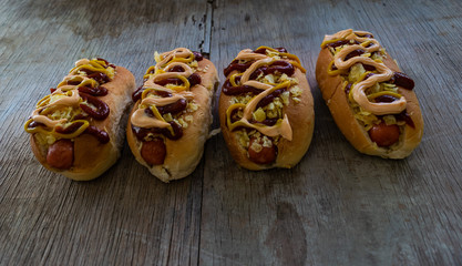 cuatro perros calientes sobre tabla de madera rustica 
