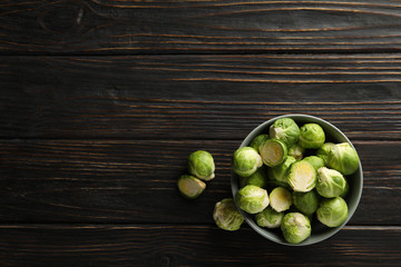 Bowl with brussels sprout on wooden background, top view