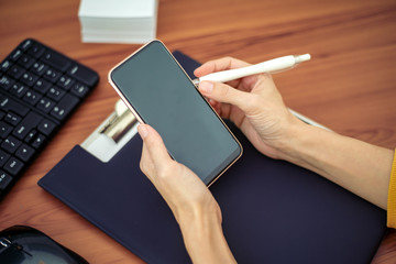 Woman using phone in office on desk.