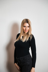 Fototapeta premium Beautiful glamour long hair woman posing for camera photographer wearing plack body with jeans - Portrait at a grey seamless background studio wall