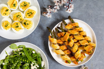 Aspargus wrapped in puff pastry and devilled eggs canapes on the white plate