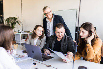 Group of happy diverse male and female business people in formal gathered around laptop computer in office