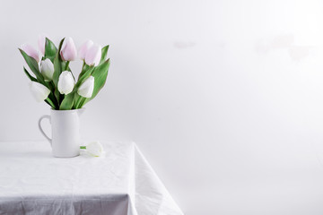 Bunch ofwhite and pink tulips in a white vase on white table