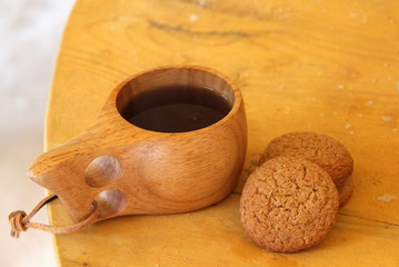 Still life of a wooden mug and cookies on a wooden table.