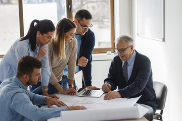 Architecture professor examining blueprint with group of his students.