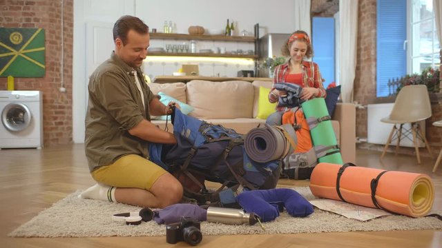 Happy couple packing clothes into travel backpacks