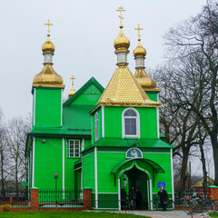 Fototapeta na wymiar Close-up orthodox wooden green church with golden domes. Religion and Easter concept.