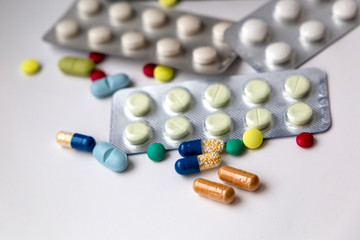 Treatment blisters with different pills and medicine with whole pack on the background. Choosing right treatment