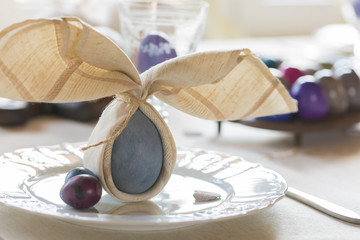 Easter festive spring table setting decoration, bunny ears shaped napkin on the plate, dyed eggs,...