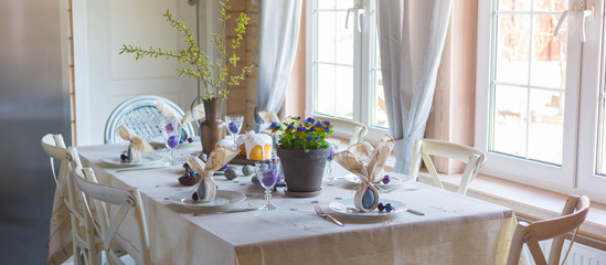Easter festive spring table setting decoration, bunny ears shaped napkins, dyed eggs, cakes, flowers, selective focus - Powered by Adobe