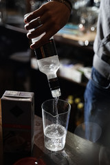 bartender pour vodka into a transparent carafe